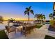 Relaxing backyard space at dusk with water views and an outdoor fireplace, surrounded by lush palms at 5128 W Longfellow Ave, Tampa, FL 33629