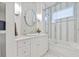 Bright bathroom featuring an oval mirror, stylish light fixtures, and a shower with glass doors at 5128 W Longfellow Ave, Tampa, FL 33629