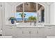 Bright white kitchen sink with white countertops offers stunning ocean views from a large arched window at 5128 W Longfellow Ave, Tampa, FL 33629