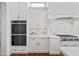 Bright white kitchen with stainless steel appliances, including oven and marble backsplash at 5128 W Longfellow Ave, Tampa, FL 33629