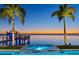 Beautiful blue-water pool with a spa and dock, set against a stunning sunset over the water at 5128 W Longfellow Ave, Tampa, FL 33629