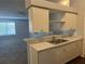 Open kitchen with stainless steel sink, white cabinets, and peninsula counter at 5904 Willow Ridge Dr # 202, Zephyrhills, FL 33541