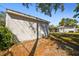 View of the backyard and detached garage and partially fenced in yard with mature trees at 6202 Tennessee Ave, New Port Richey, FL 34653