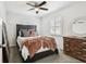 Bright bedroom featuring a ceiling fan, plantation shutters, and a dark wood bed frame at 6202 Tennessee Ave, New Port Richey, FL 34653