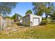View of the detached garage with a garage door in the partially fenced in backyard at 6202 Tennessee Ave, New Port Richey, FL 34653