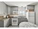 Well-lit gray kitchen with white appliances, granite countertops, and a round table with distressed paint at 6202 Tennessee Ave, New Port Richey, FL 34653