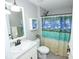 Well-maintained bathroom with a vanity, mirror, and a shower with a tropical-themed curtain at 7771 Davie Ray Dr, Zephyrhills, FL 33540