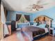 Well-lit bedroom with barn-style headboard, wooden floors, and brown curtains at 7843 Shoupe Rd, Plant City, FL 33565