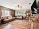 Spacious living room with wood paneling, two sofas, wood-look flooring, and ceiling fan at 7843 Shoupe Rd, Plant City, FL 33565