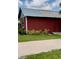 Exterior shot of a charming red barn with a metal roof and beautiful landscaping at 7843 Shoupe Rd, Plant City, FL 33565