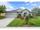 Charming single-story home featuring a well-manicured lawn, mature landscaping, and a two-car garage at 8961 Garden Party Dr, Land O Lakes, FL 34637