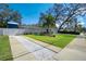 Charming home exterior with a well-manicured lawn, palm trees, and a driveway at 1009 Brookside Dr, Clearwater, FL 33764