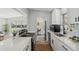 Modern kitchen featuring white cabinets, stainless steel appliances, quartz countertops, and an open view to the living area at 101 Sunlit Cove Ne Dr, St Petersburg, FL 33702