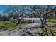 Charming single-story home featuring a metal roof, a well-manicured lawn, and mature trees providing ample shade at 1019 Canal St, Ruskin, FL 33570
