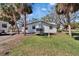 Exterior shot of a white house with black trim and an air conditioning unit surrounded by palm trees and green grass at 1019 Canal St, Ruskin, FL 33570