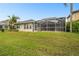Spacious backyard with tropical landscaping and screened-in pool area at 1204 Blackrush Dr, Tarpon Springs, FL 34689