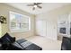 Bedroom featuring a ceiling fan, white closet doors, a grey sofa, and lots of natural light at 1204 Blackrush Dr, Tarpon Springs, FL 34689