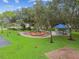 Community playground features lush green grass, mature trees, and a covered picnic area for residents at 1204 Blackrush Dr, Tarpon Springs, FL 34689