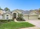 Inviting home featuring a lush green lawn, beautiful landscaping, and a spacious three-car garage at 1204 Blackrush Dr, Tarpon Springs, FL 34689