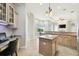Open kitchen with granite countertops, island, desk, and views into living area at 1204 Blackrush Dr, Tarpon Springs, FL 34689