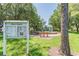 Park sign shows the community events board with park in background, featuring a playground and picnic tables at 1204 Blackrush Dr, Tarpon Springs, FL 34689
