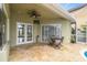 Covered outdoor patio with travertine tile, ceiling fan, and outdoor seating area at 1204 Blackrush Dr, Tarpon Springs, FL 34689