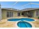 Screened-in Kidney-shaped pool with spa, travertine deck, and covered patio at 1204 Blackrush Dr, Tarpon Springs, FL 34689