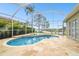 Screened-in Kidney-shaped pool with spa, travertine deck, and waterfront views at 1204 Blackrush Dr, Tarpon Springs, FL 34689