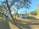 The back of this home features white siding, a brick chimney and mature shade trees at 12272 Eakin St, Weeki Wachee, FL 34614