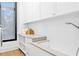 Bright laundry room showcasing white cabinets, subway tile backsplash, and a convenient pet washing station at 1401 Brightwaters Ne Blvd, St Petersburg, FL 33704