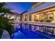 A luxurious pool is lit up blue at night with an outdoor living space and outdoor kitchen in the background at 1401 Brightwaters Ne Blvd, St Petersburg, FL 33704