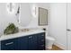 Stylish powder room with a navy vanity, marble countertop, oval mirror, and modern sconces at 1401 Brightwaters Ne Blvd, St Petersburg, FL 33704