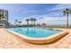 Large community pool surrounded by palm trees, lounge chairs and tiki umbrellas overlooking the ocean at 1460 Gulf Blvd # 506, Clearwater Beach, FL 33767