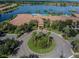 Aerial view of a resort-style clubhouse with pool, palm trees, and manicured landscaping at 15728 Aurora Lake Cir, Wimauma, FL 33598