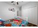 Well-lit bedroom featuring a ceiling fan, closet, bed with blue race car sheets and a modern decor at 1593 Secluded Garden Ln, Lutz, FL 33558