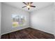 Bright bedroom with a large window, ceiling fan, and sleek wood-look tile flooring at 1593 Secluded Garden Ln, Lutz, FL 33558