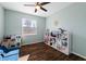 Bright and airy playroom with a ceiling fan, play kitchen, shelving unit and blue sofa at 1593 Secluded Garden Ln, Lutz, FL 33558
