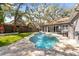 Serene backyard oasis with a crystal-clear pool, relaxing spa, and ample patio space at 1708 Country Trails Dr, Safety Harbor, FL 34695