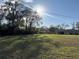 Expansive front yard featuring a home with a well-manicured lawn and mature trees at 18401 Hamilton Rd, Dade City, FL 33523