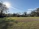 Front yard with a lush green lawn, mature trees, and a view of the home at 18401 Hamilton Rd, Dade City, FL 33523