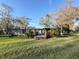 Exterior view of a well-maintained home with a spacious green lawn and mature trees at 18401 Hamilton Rd, Dade City, FL 33523