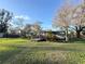 Exterior view of a well-maintained home with a green lawn and mature trees at 18401 Hamilton Rd, Dade City, FL 33523