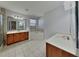 Bathroom featuring double sinks, a soaking tub, tile floors, and wood cabinets at 20342 Merry Oak Ave, Tampa, FL 33647