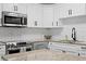 A kitchen featuring stainless steel appliances, white cabinets, and granite countertops with a herringbone tile backsplash at 2912 W Winthrop Rd, Tampa, FL 33611