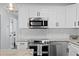 Modern kitchen featuring stainless steel appliances, white cabinets, and a stylish herringbone tile backsplash at 2912 W Winthrop Rd, Tampa, FL 33611
