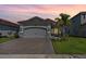 Beautiful home with lush lawn, stone accents, brick driveway and a two-car garage at sunset at 31046 Lindentree Dr, Wesley Chapel, FL 33543
