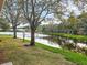 Backyard view featuring a pond, mature trees and landscaping at 3876 Timber Ridge Ct, Palm Harbor, FL 34685