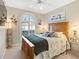 Cozy main bedroom with a wooden bed frame, fan, and natural light streaming through the windows at 3876 Timber Ridge Ct, Palm Harbor, FL 34685