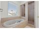 Bright bathroom with a soaking tub, a view through the window, and a glass-enclosed walk-in shower at 436 St Andrews Dr, Belleair, FL 33756