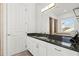 Bathroom featuring a sleek vanity with dark granite countertops and white cabinetry, plus an illuminated mirror at 436 St Andrews Dr, Belleair, FL 33756